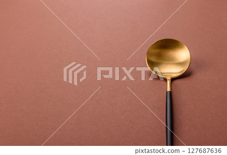 Empty metal spoon on a monochrome brown background Empty metal spoon on a monochrome brown background 127687636