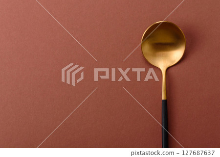 Empty metal spoon on a monochrome brown background Empty metal spoon on a monochrome brown background 127687637