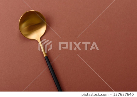 Empty metal spoon on a monochrome brown background Empty metal spoon on a monochrome brown background 127687640