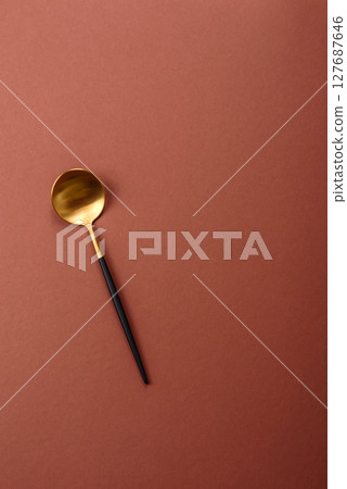 Empty metal spoon on a monochrome brown background 127687646