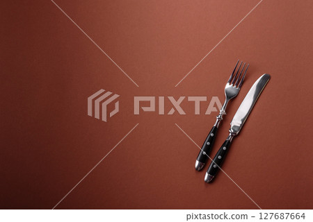 Knife and fork, cutlery on a brown dining table 127687664