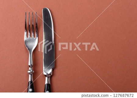 Knife and fork, cutlery on a brown dining table 127687672