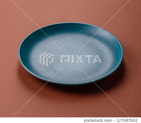 Empty ceramic plate on a monochrome brown background 127687682