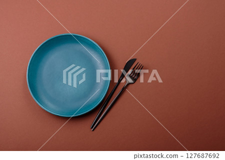 Empty ceramic plate on a monochrome brown background 127687692