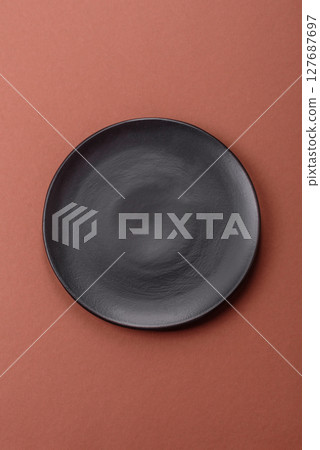 Empty ceramic plate on a monochrome brown background Empty ceramic plate on a monochrome brown background 127687697