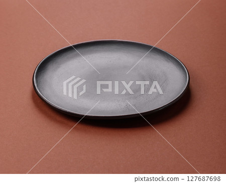 Empty ceramic plate on a monochrome brown background 127687698