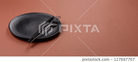 Empty ceramic plate on a monochrome brown background 127687707