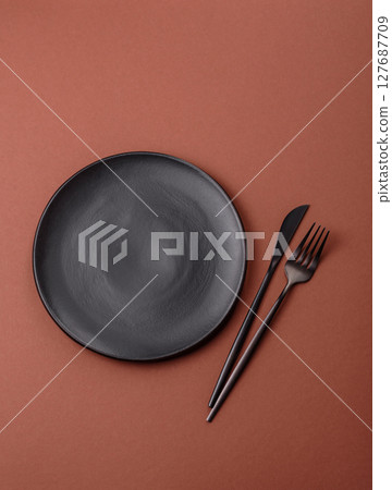 Empty ceramic plate on a monochrome brown background 127687709