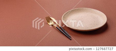 Empty ceramic plate on a monochrome brown background 127687727