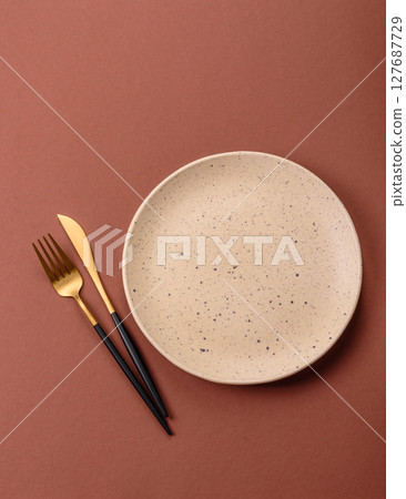 Empty ceramic plate on a monochrome brown background Empty ceramic plate on a monochrome brown background 127687729