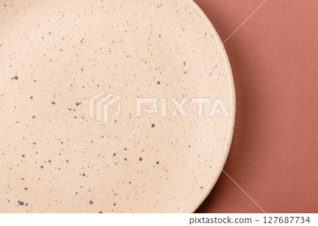 Empty ceramic plate on a monochrome brown background 127687734