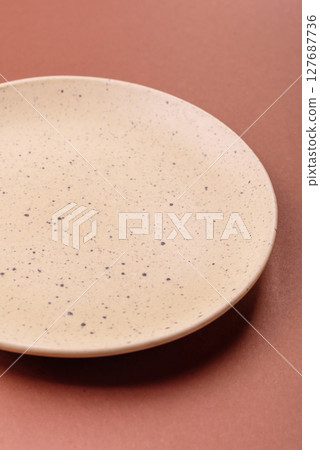 Empty ceramic plate on a monochrome brown background Empty ceramic plate on a monochrome brown background 127687736