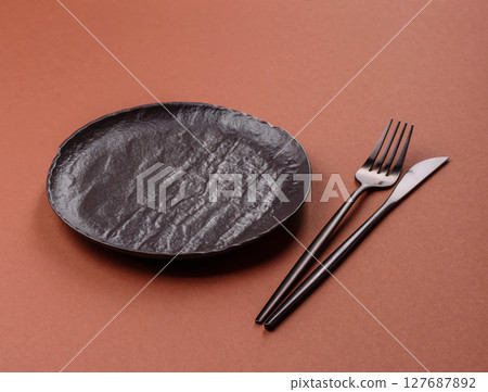 Empty ceramic plate on a monochrome brown background 127687892