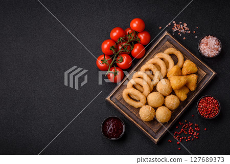 Food, chicken nuggets, onion rings and cheese balls on dark background Food, chicken nuggets, onion rings and cheese balls on dark background 127689373