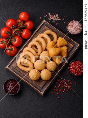 Food, chicken nuggets, onion rings and cheese balls on dark background 127689374