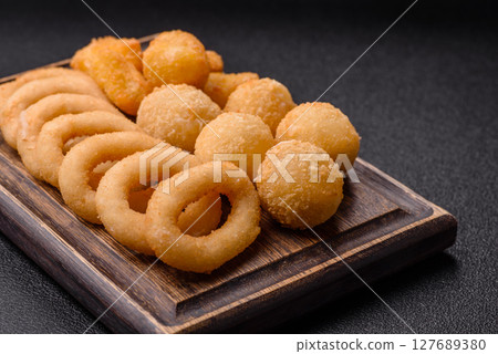Food, chicken nuggets, onion rings and cheese balls on dark background 127689380