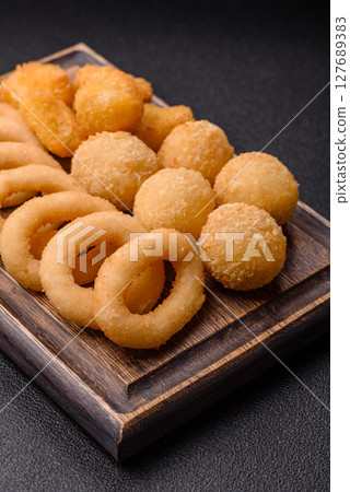 Food, chicken nuggets, onion rings and cheese balls on dark background 127689383