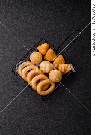 Food, chicken nuggets, onion rings and cheese balls on dark background Food, chicken nuggets, onion rings and cheese balls on dark background 127689389