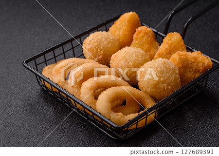 Food, chicken nuggets, onion rings and cheese balls on dark background Food, chicken nuggets, onion rings and cheese balls on dark background 127689391