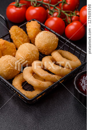 Food, chicken nuggets, onion rings and cheese balls on dark background Food, chicken nuggets, onion rings and cheese balls on dark background 127689398