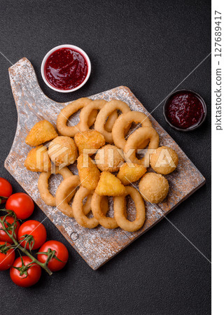 Food, chicken nuggets, onion rings and cheese balls on dark background Food, chicken nuggets, onion rings and cheese balls on dark background 127689417