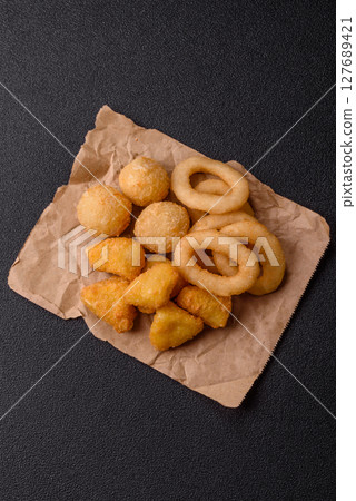 Food, chicken nuggets, onion rings and cheese balls on dark background 127689421