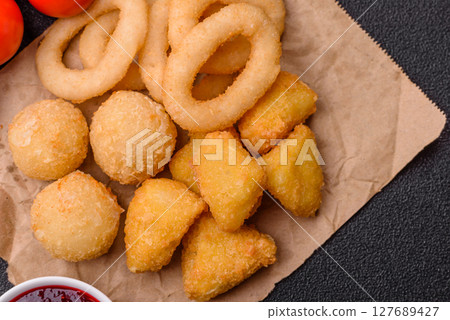 Food, chicken nuggets, onion rings and cheese balls on dark background Food, chicken nuggets, onion rings and cheese balls on dark background 127689427