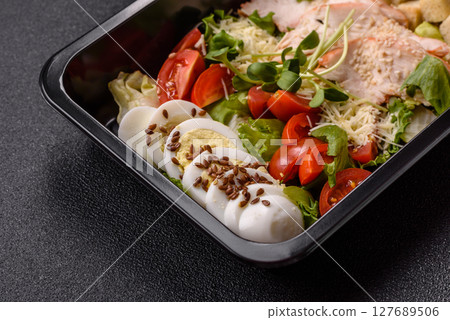 Bowl with caesar salad with chicken, parmesan cheese, tomatoes, croutons, lettuce leaves 127689506