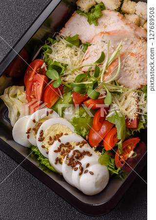 Bowl with caesar salad with chicken, parmesan cheese, tomatoes, croutons, lettuce leaves 127689508