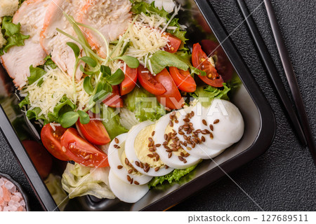 Bowl with caesar salad with chicken, parmesan cheese, tomatoes, croutons, lettuce leaves 127689511