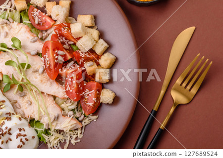 Bowl with caesar salad with chicken, parmesan cheese, tomatoes, croutons, lettuce leaves 127689524