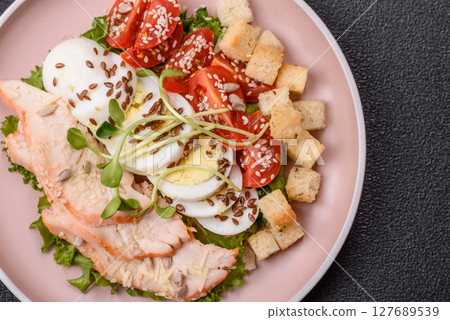 Bowl with caesar salad with chicken, parmesan cheese, tomatoes, croutons, lettuce leaves 127689539