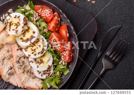 Bowl with caesar salad with chicken, parmesan cheese, tomatoes, croutons, lettuce leaves 127689555