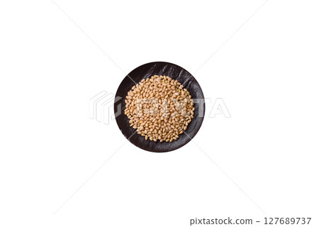 Peeled pine nuts in a bowl on a white background 127689737