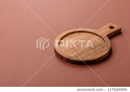 Empty wooden cutting board on a monochrome brown background 127689909
