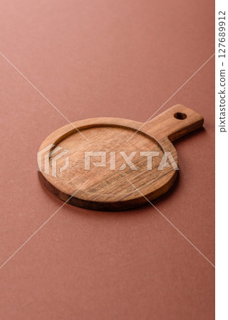 Empty wooden cutting board on a monochrome brown background Empty wooden cutting board on a monochrome brown background 127689912