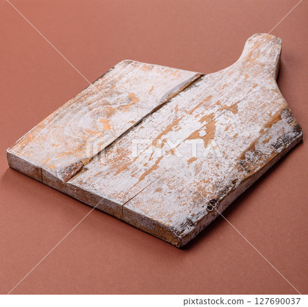 Empty wooden cutting board on a monochrome brown background Empty wooden cutting board on a monochrome brown background 127690037