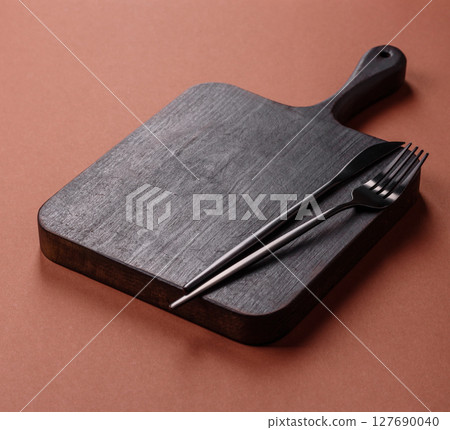Empty wooden cutting board on a monochrome brown background 127690040