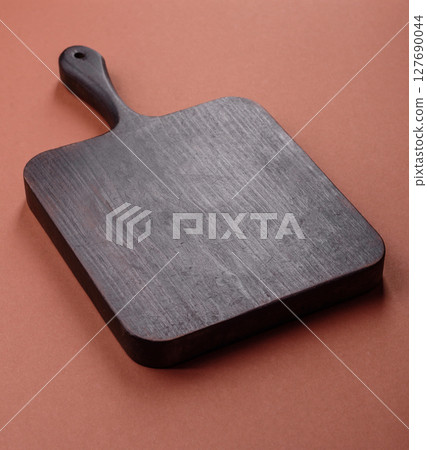 Empty wooden cutting board on a monochrome brown background 127690044