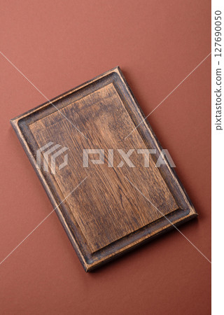 Empty wooden cutting board on a monochrome brown background Empty wooden cutting board on a monochrome brown background 127690050