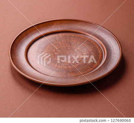 Empty ceramic plate on a monochrome brown background Empty ceramic plate on a monochrome brown background 127690068
