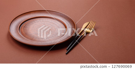 Empty ceramic plate on a monochrome brown background 127690069