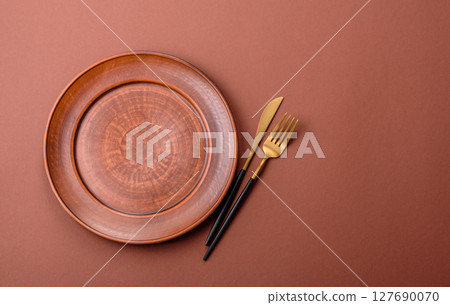 Empty ceramic plate on a monochrome brown background Empty ceramic plate on a monochrome brown background 127690070