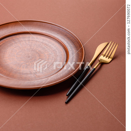 Empty ceramic plate on a monochrome brown background 127690072