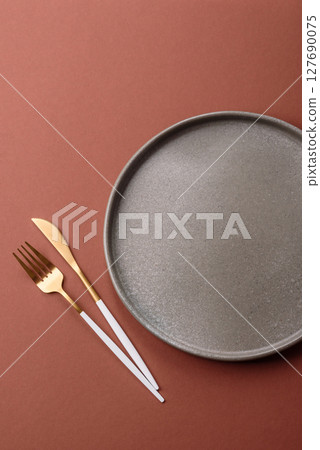 Empty ceramic plate on a monochrome brown background Empty ceramic plate on a monochrome brown background 127690075