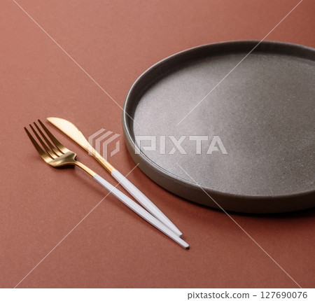Empty ceramic plate on a monochrome brown background Empty ceramic plate on a monochrome brown background 127690076