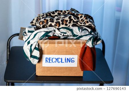 Box of used clothing marked for recycling. Eco friendly lifestyle. Closet management. 127690143