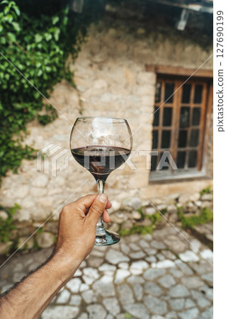 Red Wine Glass in Hand with Stone Cellar Background in France or Italy Red Wine Glass in Hand with Stone Cellar Background in France or Italy 127690199
