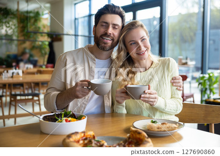 Bearded man and woman enjoying meal at restaurant with pizza and coffee cups Bearded man and woman enjoying meal at restaurant with pizza and coffee cups 127690860