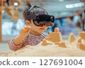 A toddler engages with a virtual sandbox using immersive technology 127691004